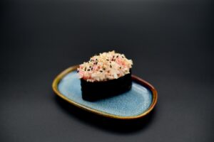 üks gunkan sinisel taldrikul, sushi riis, lumekrabi, masago kaste, nori.