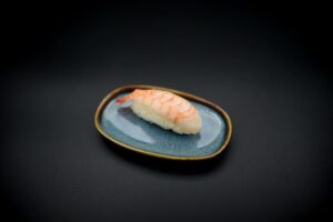 üks nigiri sinisel taldrikul, sushi riis, krevetid.