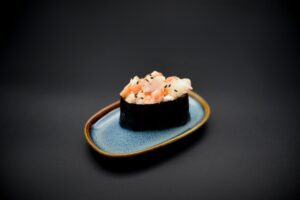 üks gunkan sinisel taldrikul, sushi riis, masago kaste, krevetid, nori.