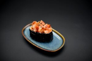 Küpsetatud gunkan sinisel taldrikul, sushi riis, nori, masago kaste, unagi, seesam, krevetid